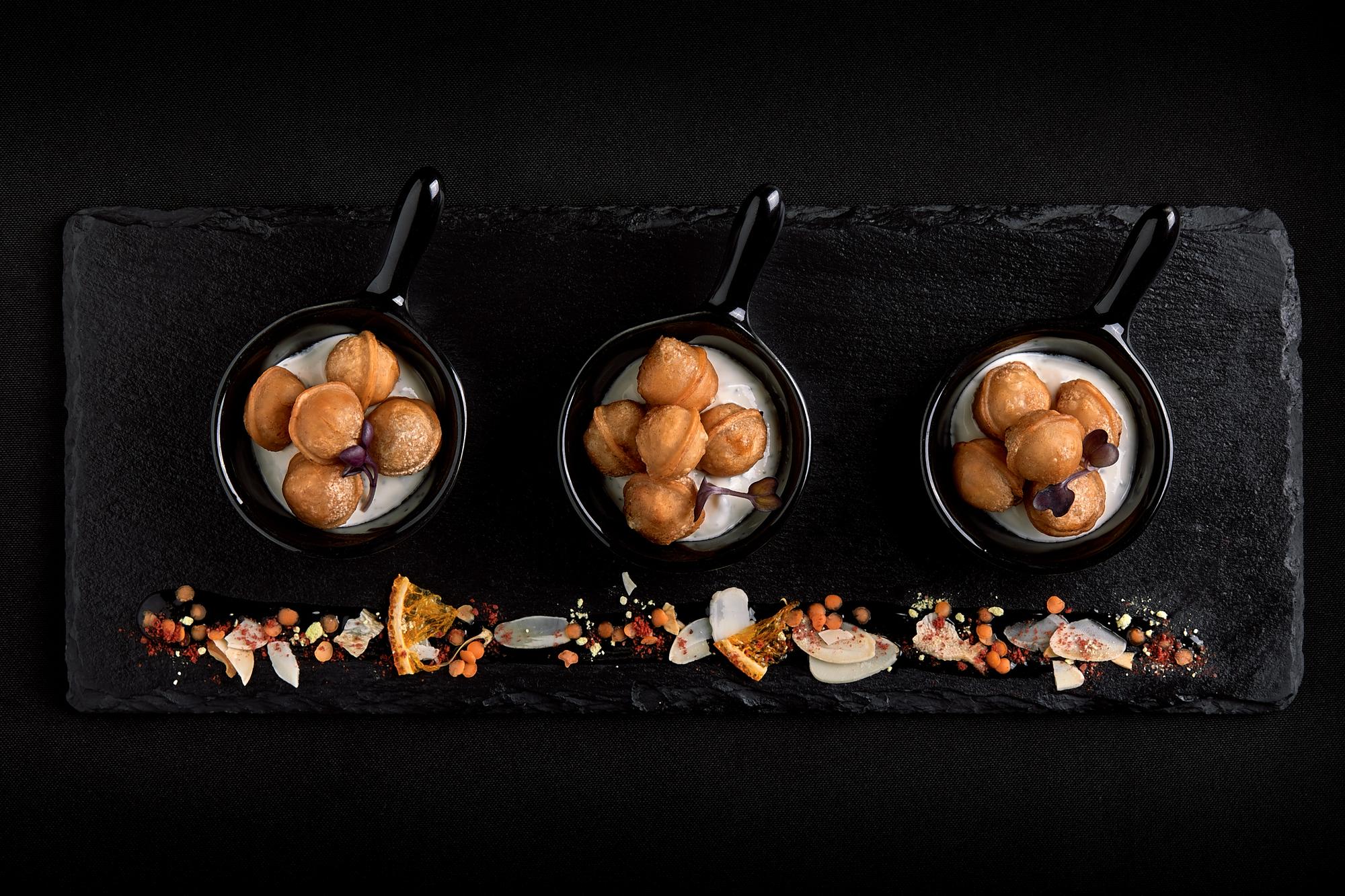 Row of plated starters on a dark table
